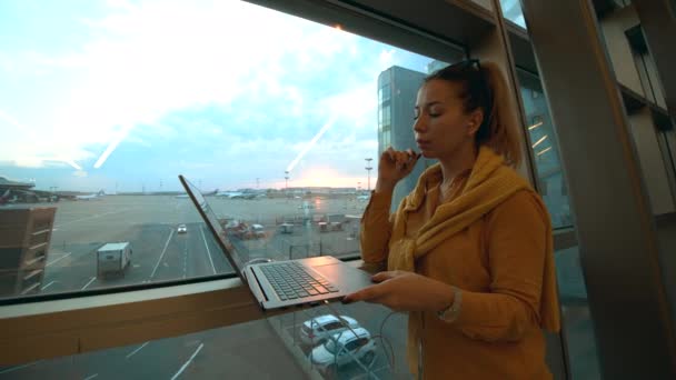 Vista lateral de una encantadora dama escribiendo en un ordenador en el aeropuerto — Vídeo de stock