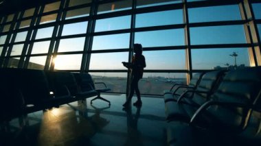 Havaalanının bekleme salonunda bir bayan dizüstü bilgisayar üzerinde çalışıyor.