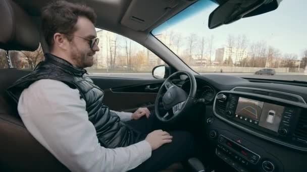 Genç adam kendi kendine park eden akıllı bir arabada oturuyor. — Stok video