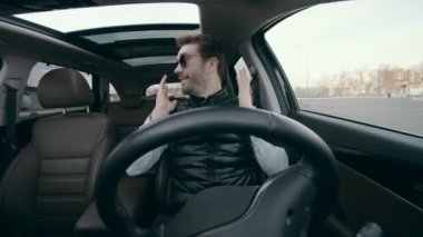 Bir adam içeride otururken araba otomatik pilotta gidiyor..