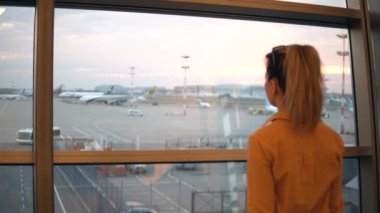 Havaalanı penceresinden bakan bir kadının arkadan görünüşü