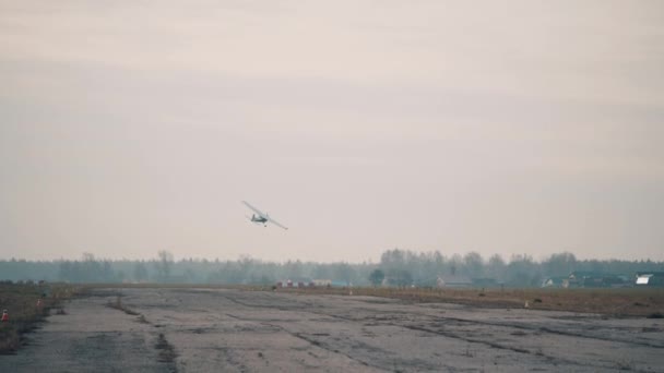 Стара злітно-посадкова смуга і маленький літак, що летить над нею — стокове відео