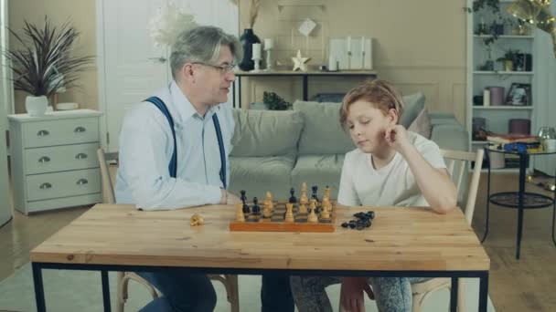 Teenage boy is playing chess with his grandfather — Stock Video