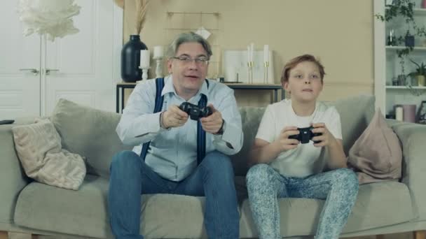 Un niño está jugando videojuegos con su abuelo — Vídeo de stock
