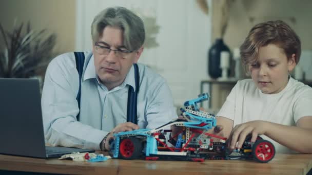 Chlapec a jeho děda spolu montují autíčko. — Stock video