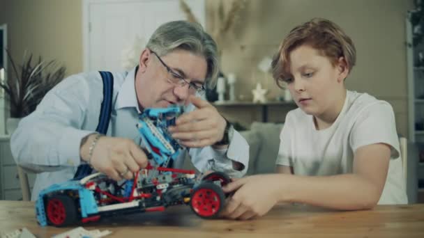 A rangidős ember összeállít egy játékautót az unokájával. — Stock videók