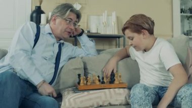 Büyükbaba torunuyla satranç oynuyor.