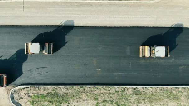 Macchine di laminazione che guidano lungo un'autostrada asfaltata. Costruzioni Lavoratori impegnati nella costruzione di strade — Video Stock