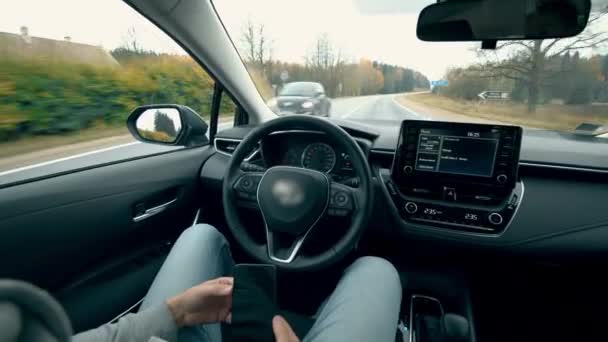 Pessoa olha para o telefone móvel enquanto sentado em um carro de auto-condução . — Vídeo de Stock