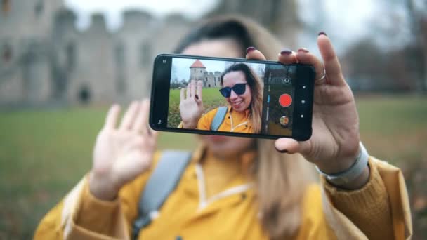 Vrouw neemt zichzelf op een telefoon op een kasteel achtergrond. — Stockvideo