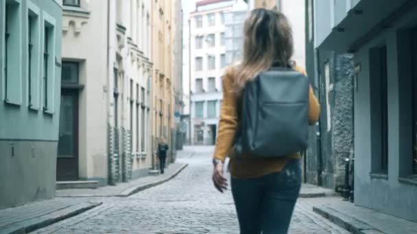 Mujer feliz caminando en una ciudad antigua con una mochila . — Vídeos de Stock
