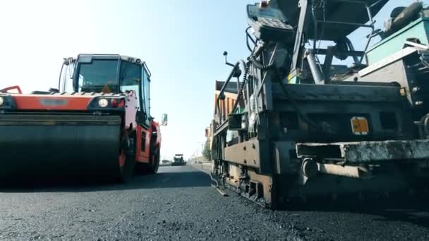 Önünde kaldırım makineleri olan yeni asfalt yol. Yol inşa süreci. — Stok video