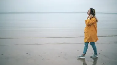 Sonbaharda kadın turist deniz kıyısında yürüyor..
