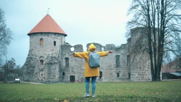 Glad turist dansar nära ett gammalt slott. — Stockvideo