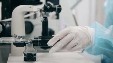 Hastane çalışanı odada mikroskop kullanıyor..