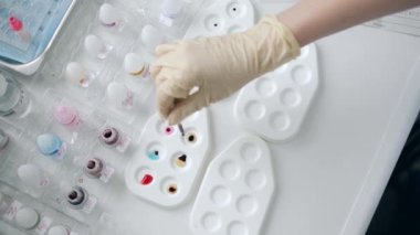 Laboratuvarda bir kişi paletlere örnek karıştırıyor..