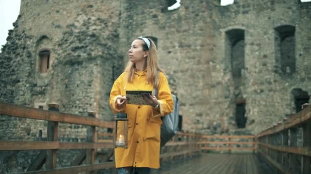 Una chica mira un mapa mientras sostiene la luz de las velas en el antiguo castillo . — Vídeos de Stock