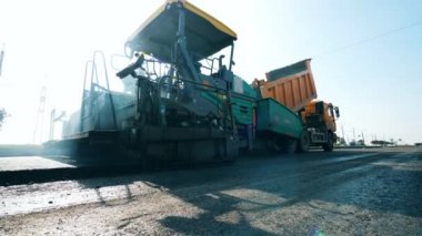 Yol yapım süreci. Bitum kamyondan yayıcıya taşınıyor.