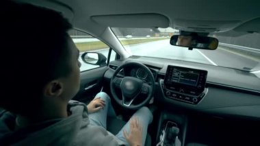 Genç adam kendi kendine giderken arabada oturur. Otomatik pilot, akıllı araç, drivelless otomobil konsepti.