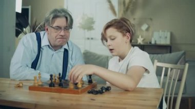 Bir çocuk ve büyükbabası satranç hakkında konuşuyorlar.
