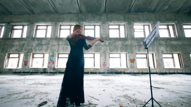 Одна женщина играет на скрипке по нотам в разрушенном здании . — стоковое видео