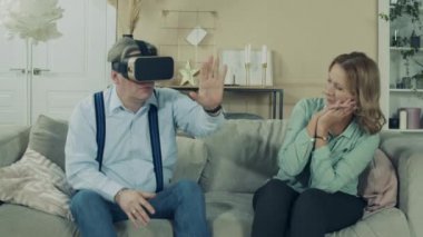 Yaşlı kadın, kocasını gözlük takarak izliyor.