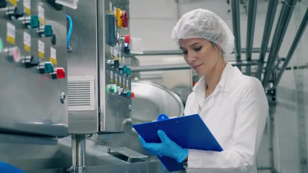 Especialista feminina está fazendo anotações de equipamentos de fábrica — Vídeo de Stock