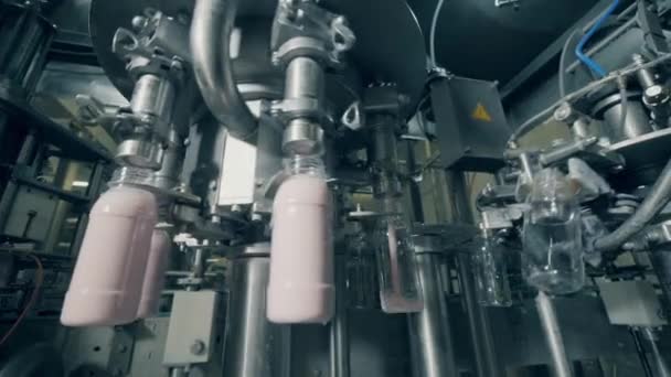 Las botellas se llenan mecánicamente con productos lácteos líquidos — Vídeos de Stock