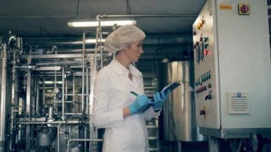 Fabrika işçisi fabrika makinelerinin notlarını alıyor.