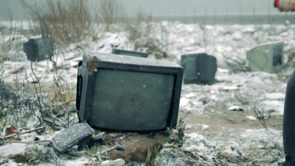 Une personne casse une télé avec un marteau dans une décharge. Un homme avec un marteau brise l'écran de télévision . — Video