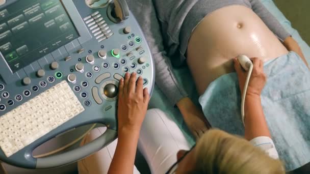 Blick von oben auf ein Bedienfeld und den Bauch der Frau während des Ultraschalls — Stockvideo