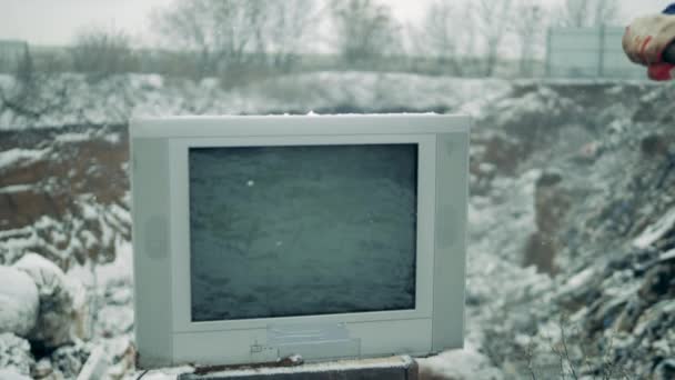 Η λευκή τηλεόραση διαλύεται με σφυρί σε μια χωματερή. Ο άνθρωπος με το σφυρί σπάει την οθόνη της τηλεόρασης. — Αρχείο Βίντεο