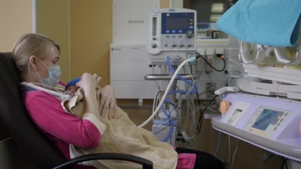 Una mujer está abrazando a un bebé recién nacido en una habitación médica — Vídeos de Stock