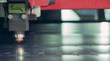 Lazer ekipmanları metal bir levhada küçük kesikler yapıyor.