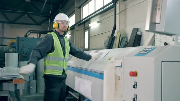 Male employee is operating a machine processing a metal sheet — Stock Video