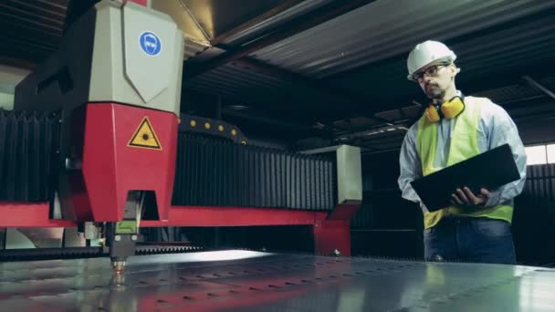 Лазерная машина режет металл под контролем мужчин — стоковое видео