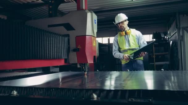 Werksarbeiter beobachtet einen Lasermechanismus, der Metall bearbeitet — Stockvideo