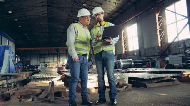 Los empleados masculinos están hablando en una unidad con materiales de construcción. Ingenieros masculinos en fábrica industrial . — Vídeos de Stock