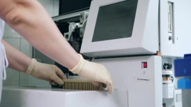 Laboratuvar uzmanı test tüplerini analiz cihazına yüklüyor.
