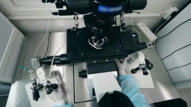 Modern bir mikroskobun ve bir laboratuvar çalışanının üst görüntüsü.