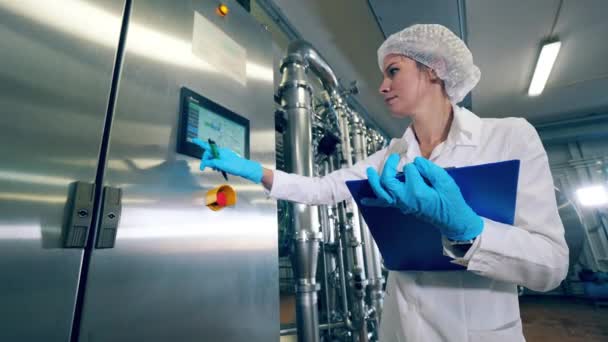 工厂工人检查一台机器,在显示器上打字. 女工控制生产设备的质量. — 图库视频影像
