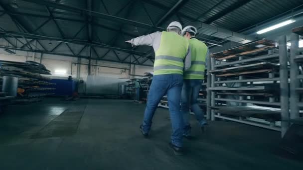 Zwei männliche Arbeiter laufen über das Fabrikgelände — Stockvideo