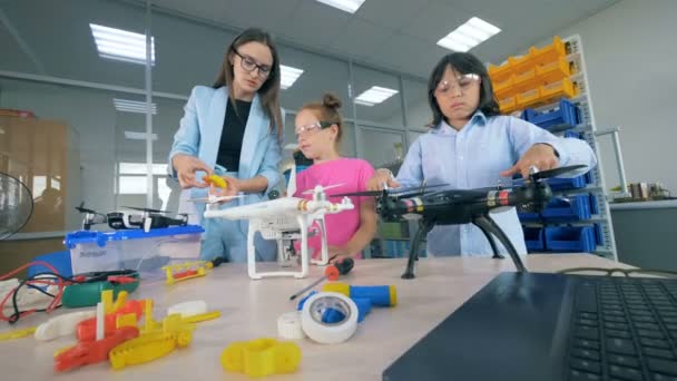 Lâminas de quadricópteros estão sendo giradas por crianças e um especialista em laboratório — Vídeo de Stock