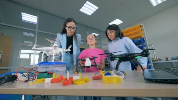 Dos adolescentes y una ingeniera femenina están observando drones. 4K . — Vídeos de Stock