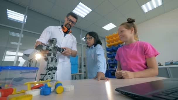 Robô de brinquedo está sendo mostrado para as crianças por um especialista em laboratório masculino — Vídeo de Stock