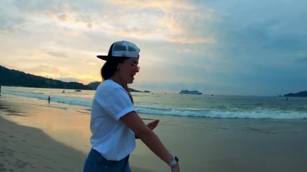 Jonge vrouw in zomerkleren loopt langs de kust — Stockvideo