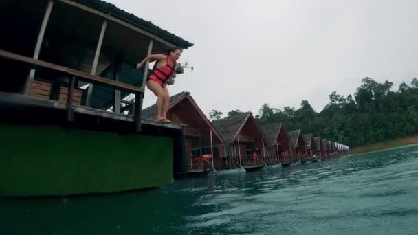 Junge Frau in Schwimmweste springt bei Regen ins Wasser — Stockvideo
