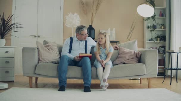 Little girl and her grandfather are reading a book — Stock Video