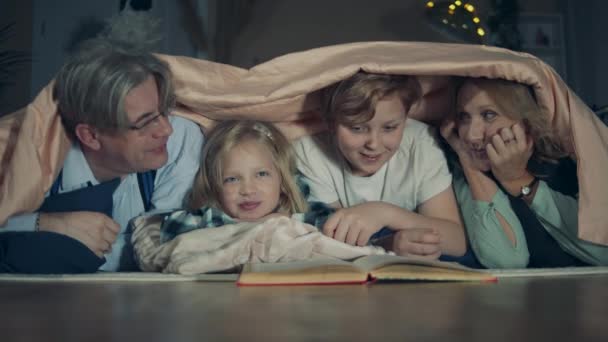 Бабушка с дедушкой и внуки разговаривают под одеялом — стоковое видео