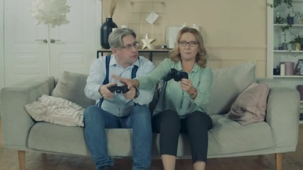 Homem e mulher idosos estão jogando um videogame em casa — Vídeo de Stock